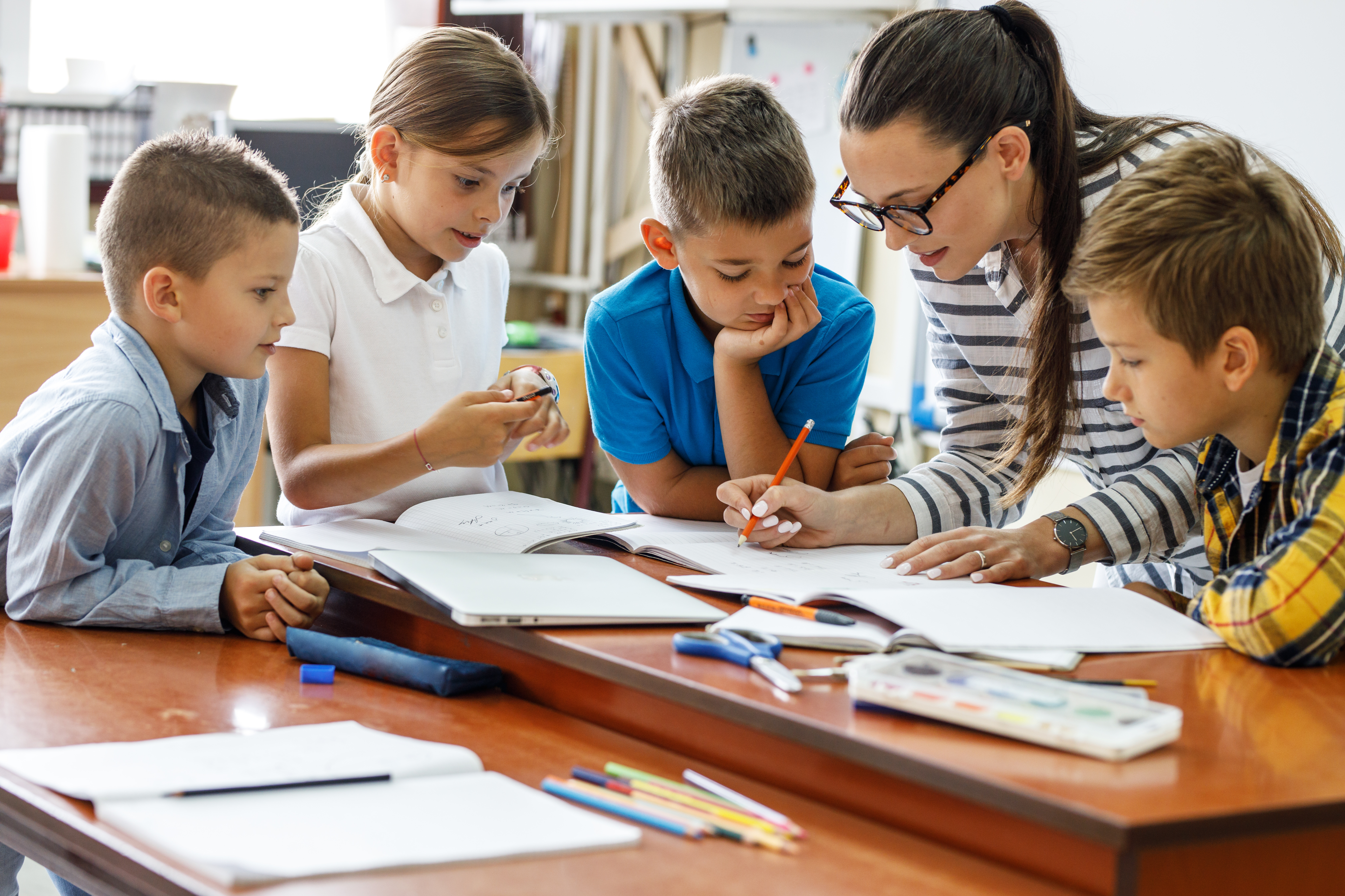 Teacher working closely with 4 young children