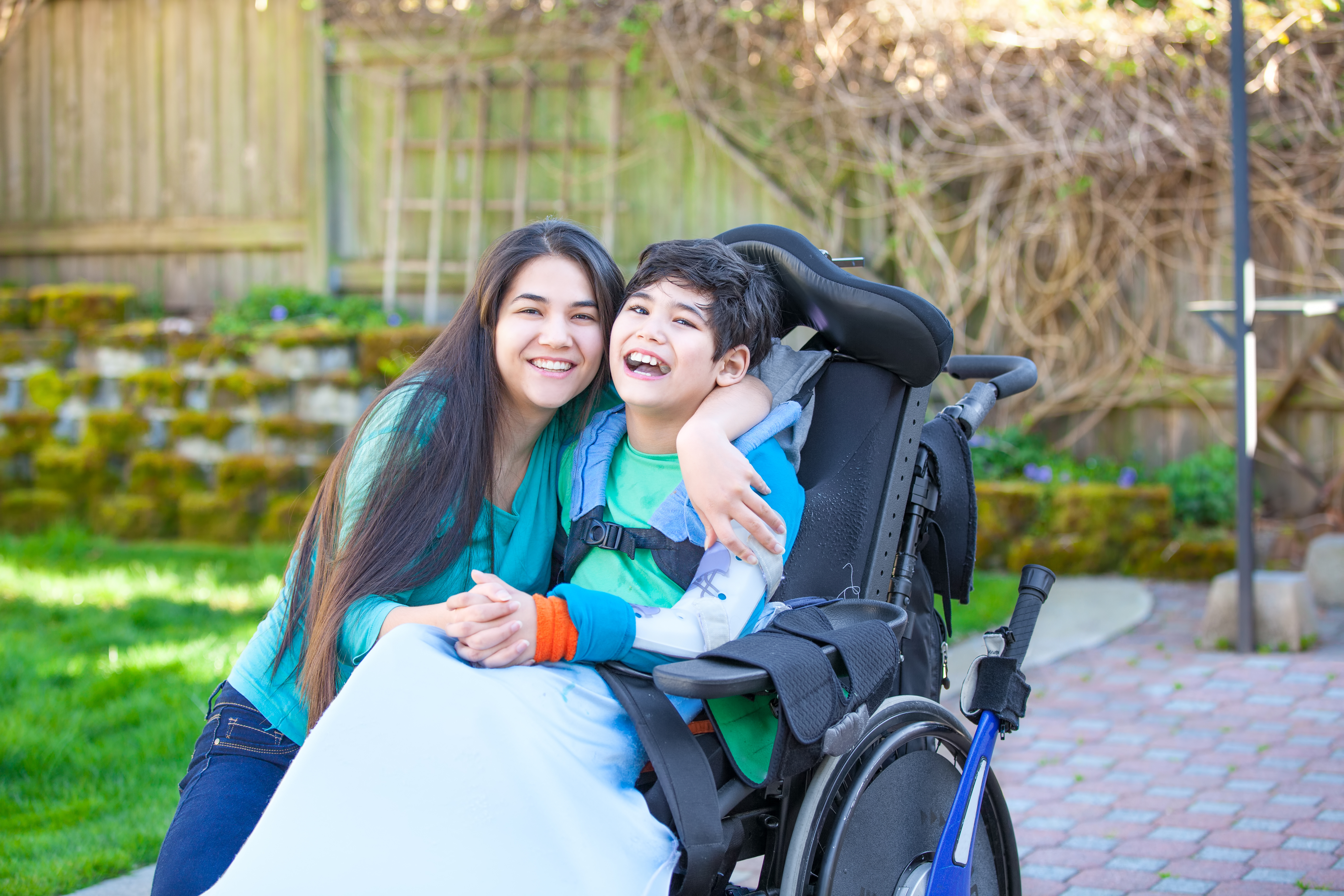 Young person in a wheelchair gets a hug from someone
